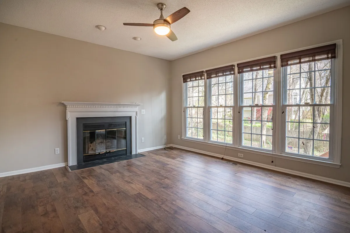 Sample living room with a fireplace and a large window, original walls